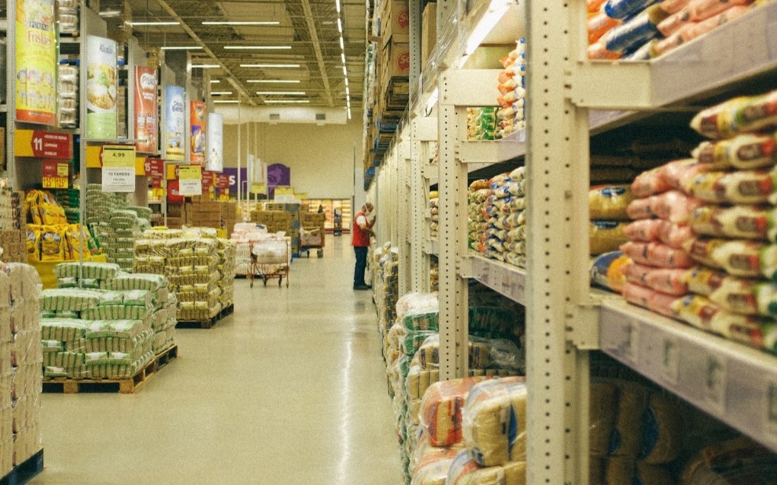 Corsia di un supermercato con scaffali e pallet carichi di sacchi di alimenti